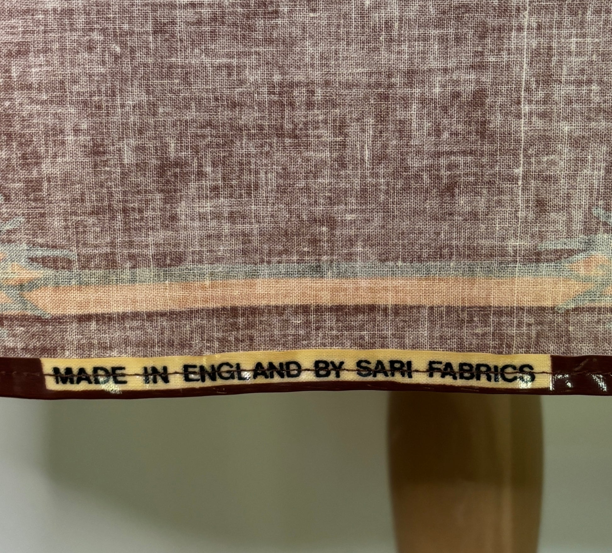Textile with a label indicating 'Made in England by Sari Fabrics' on a fabric background.