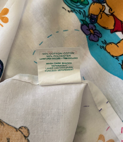Fabric with a label indicating 50% cotton and 50% polyester, featuring cartoon characters in the background.