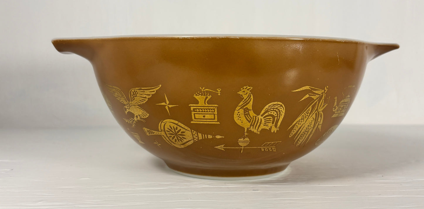 Brown mixing bowl with gold embossed designs on a white background