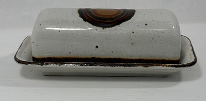 White ceramic butter dish with brown speckles on a white background