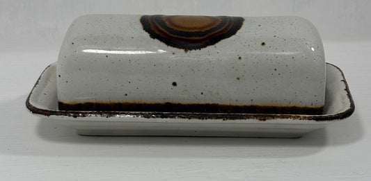 White ceramic butter dish with brown speckles on a white background