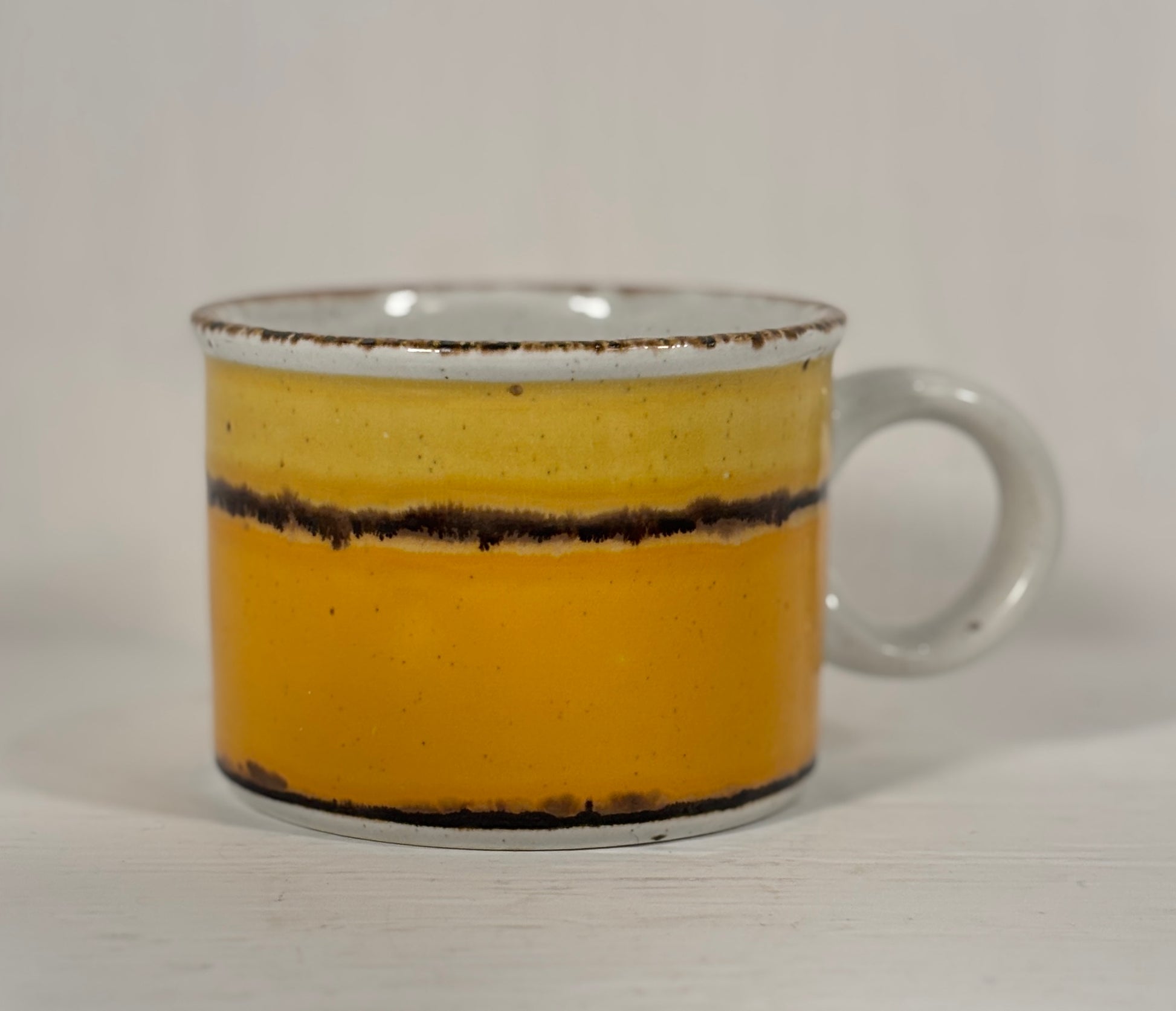 Yellow and orange mug with a brown stripe on a white background