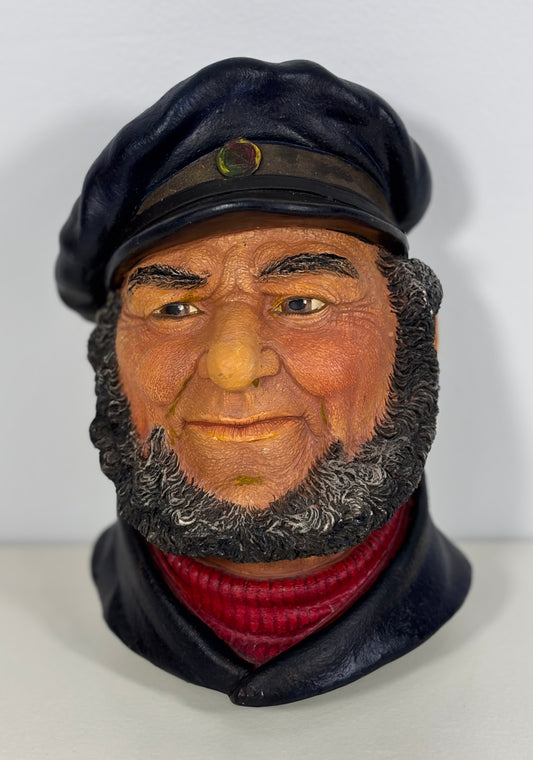 Bust of a man wearing a black cap and red sweater on a white background