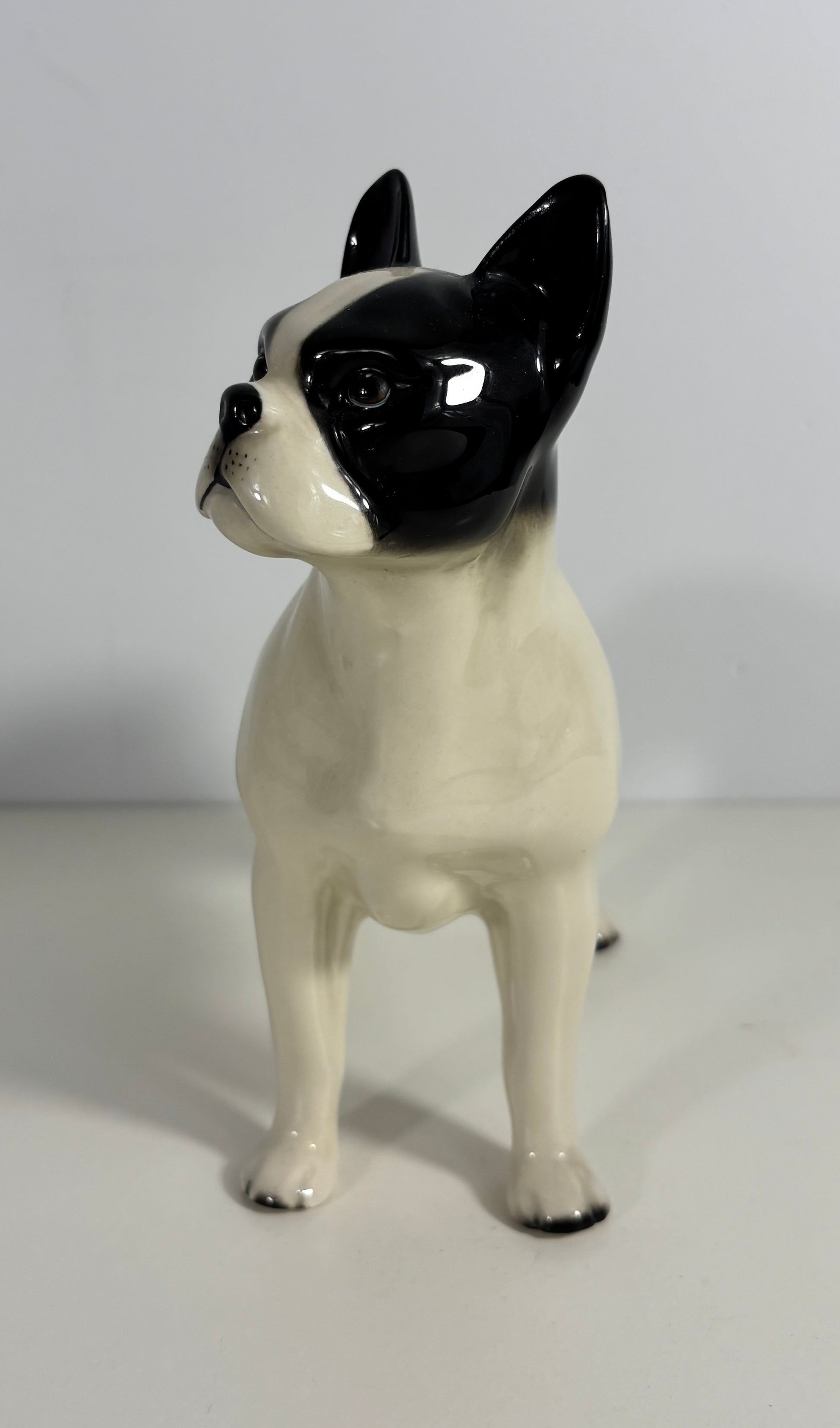 Ceramic figurine of a dog with black and white coloration on a plain background