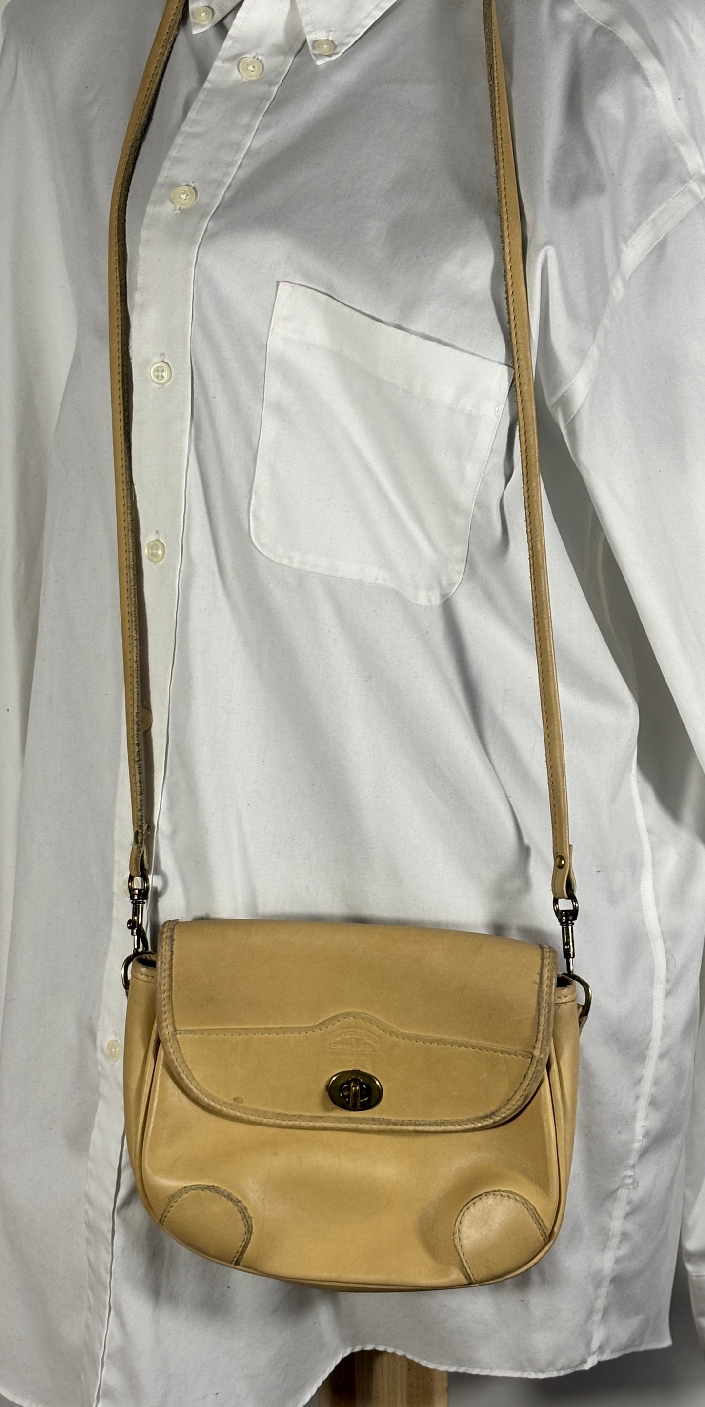 Beige handbag with a strap over a light gray shirt
