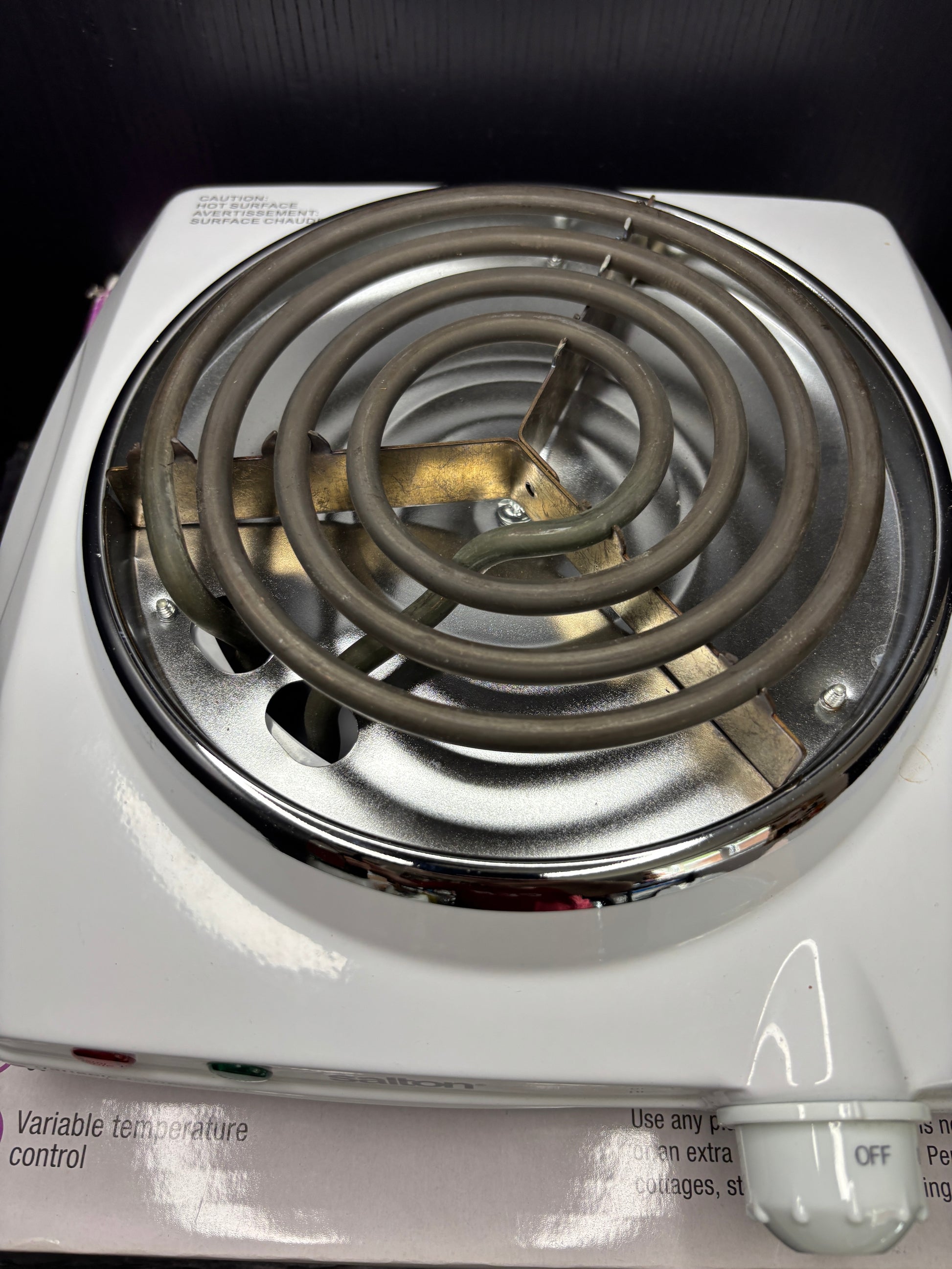 Close-up of a heating element on a white appliance with visible branding.