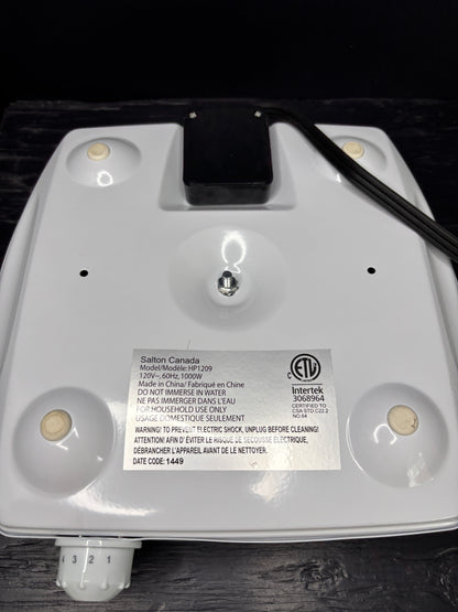 Close-up of a white electronic device with a label on a dark surface