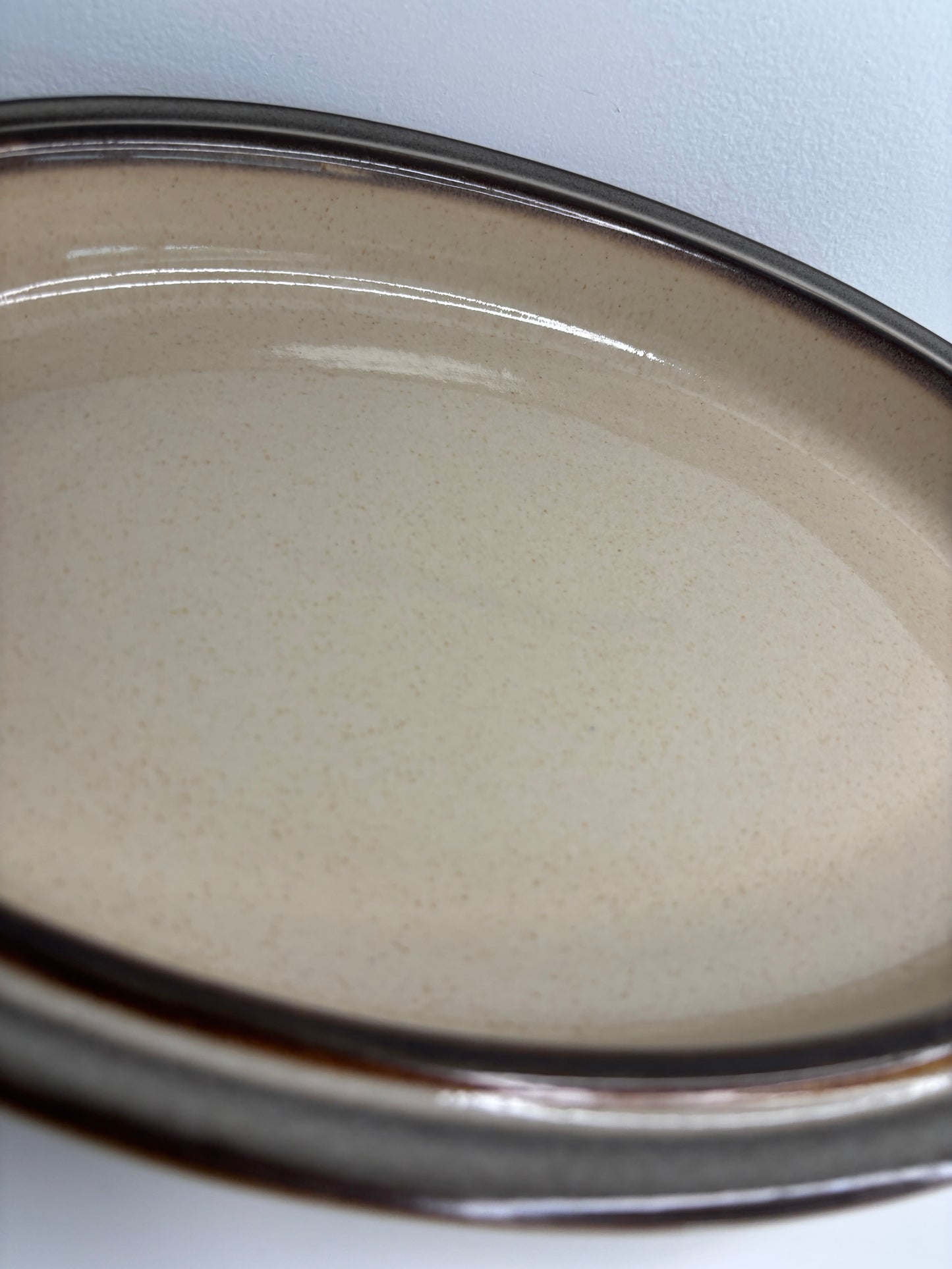 Close-up of a beige powder compact with a silver lid on a white background