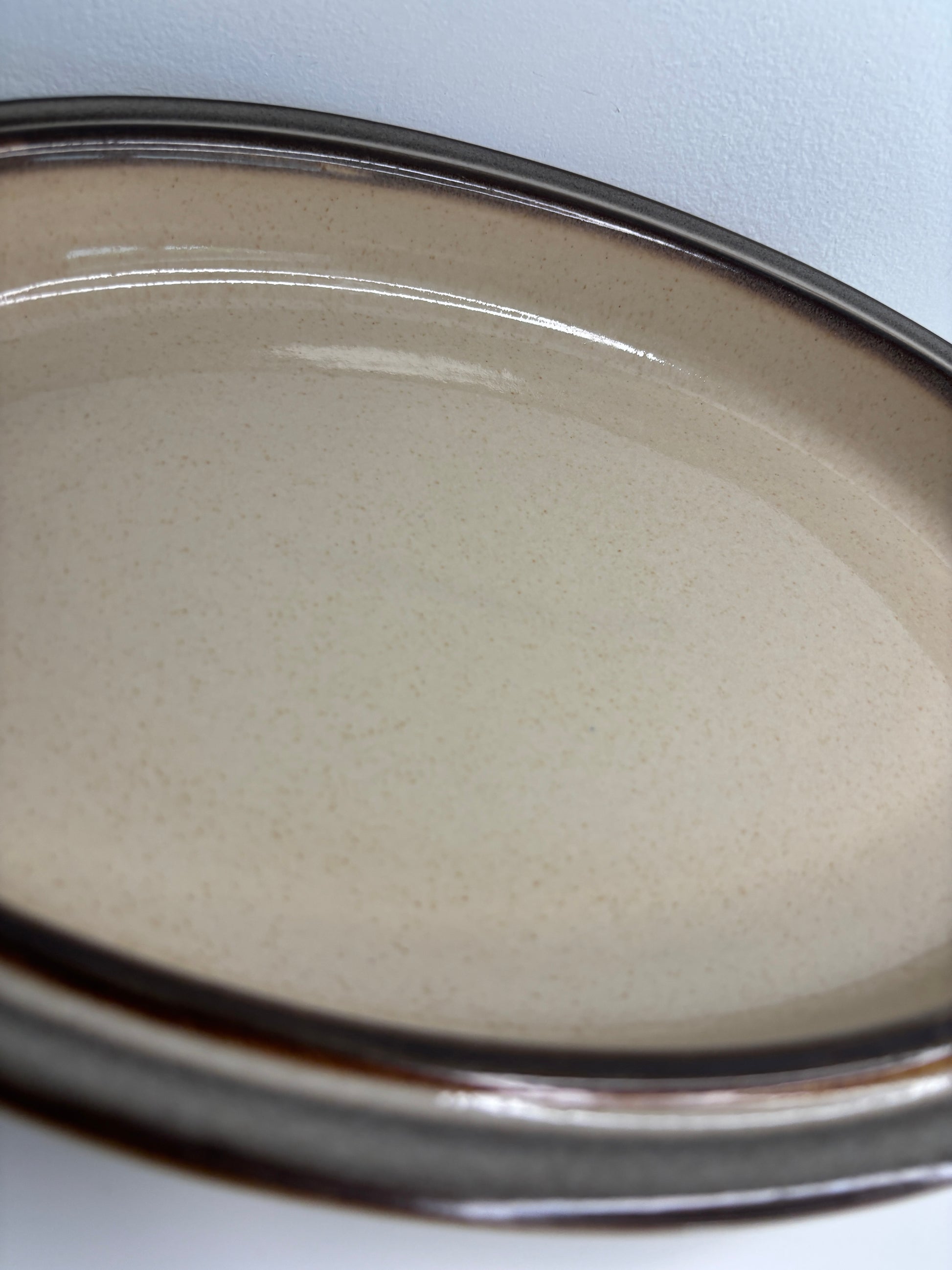 Close-up of a beige powder compact with a silver lid on a white background
