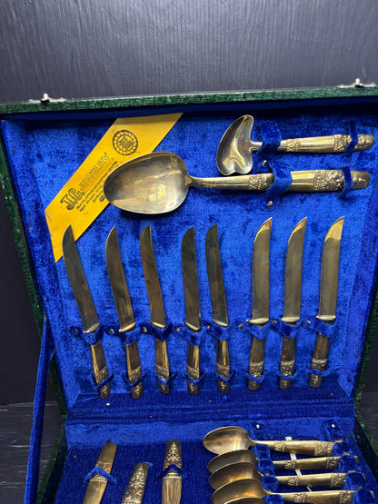 Set of silver cutlery with gold handles in a blue case.