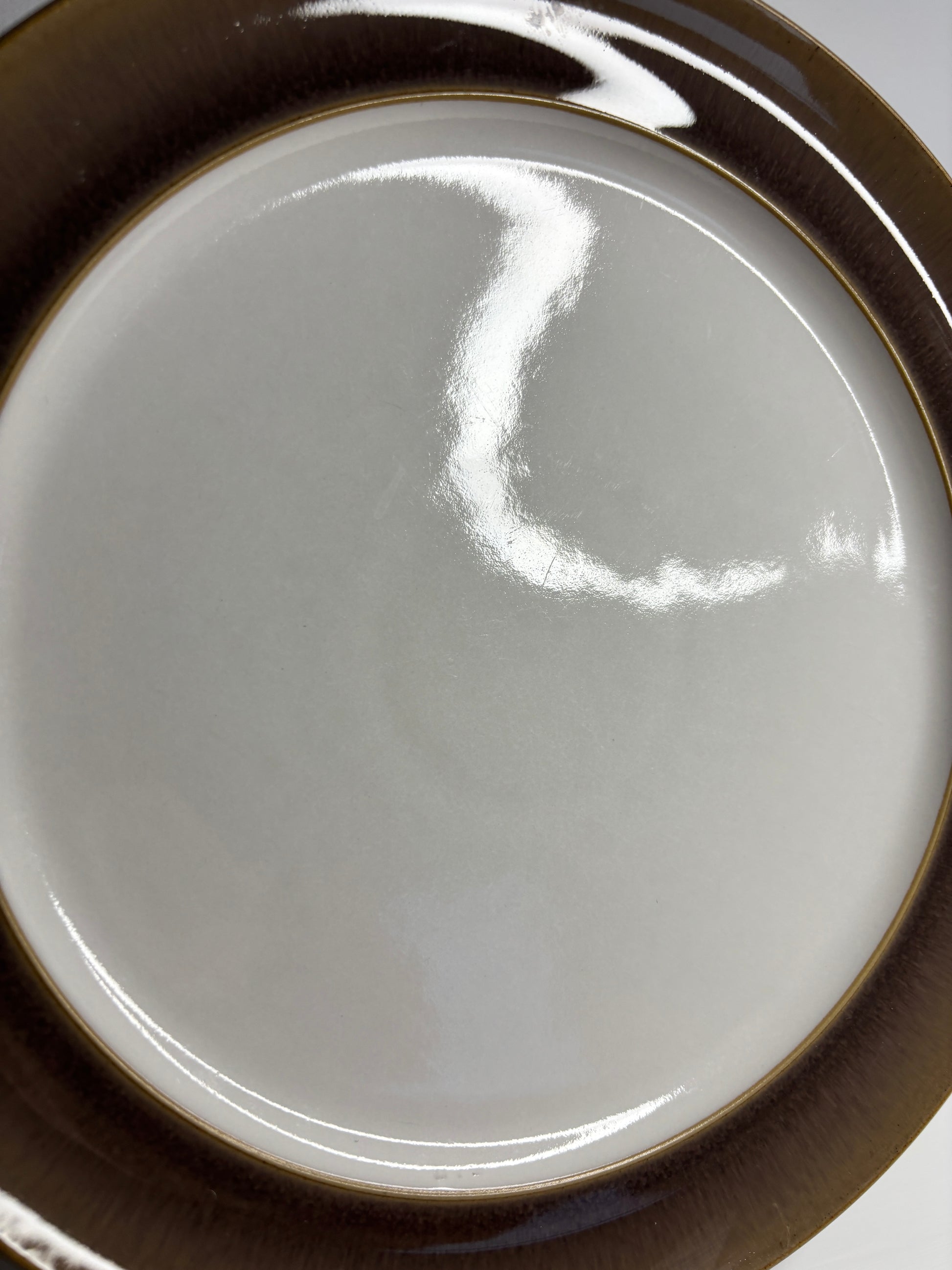 Close-up of a ceramic plate with a brown rim on a white background