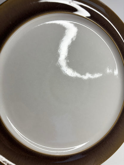Close-up of a ceramic plate with a brown rim on a white background