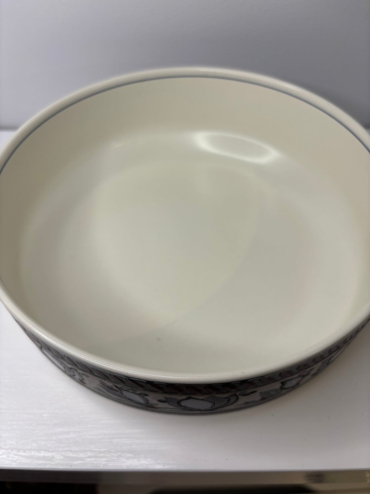 Close-up of a ceramic bowl with a white interior and black exterior design on a white background.