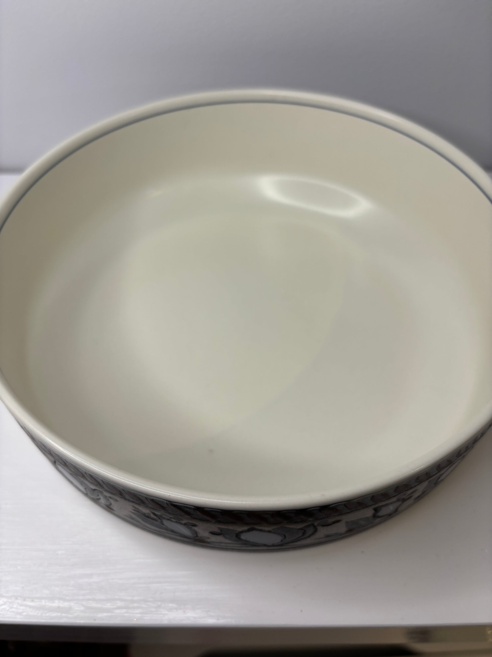Close-up of a ceramic bowl with a white interior and black exterior design on a white background.