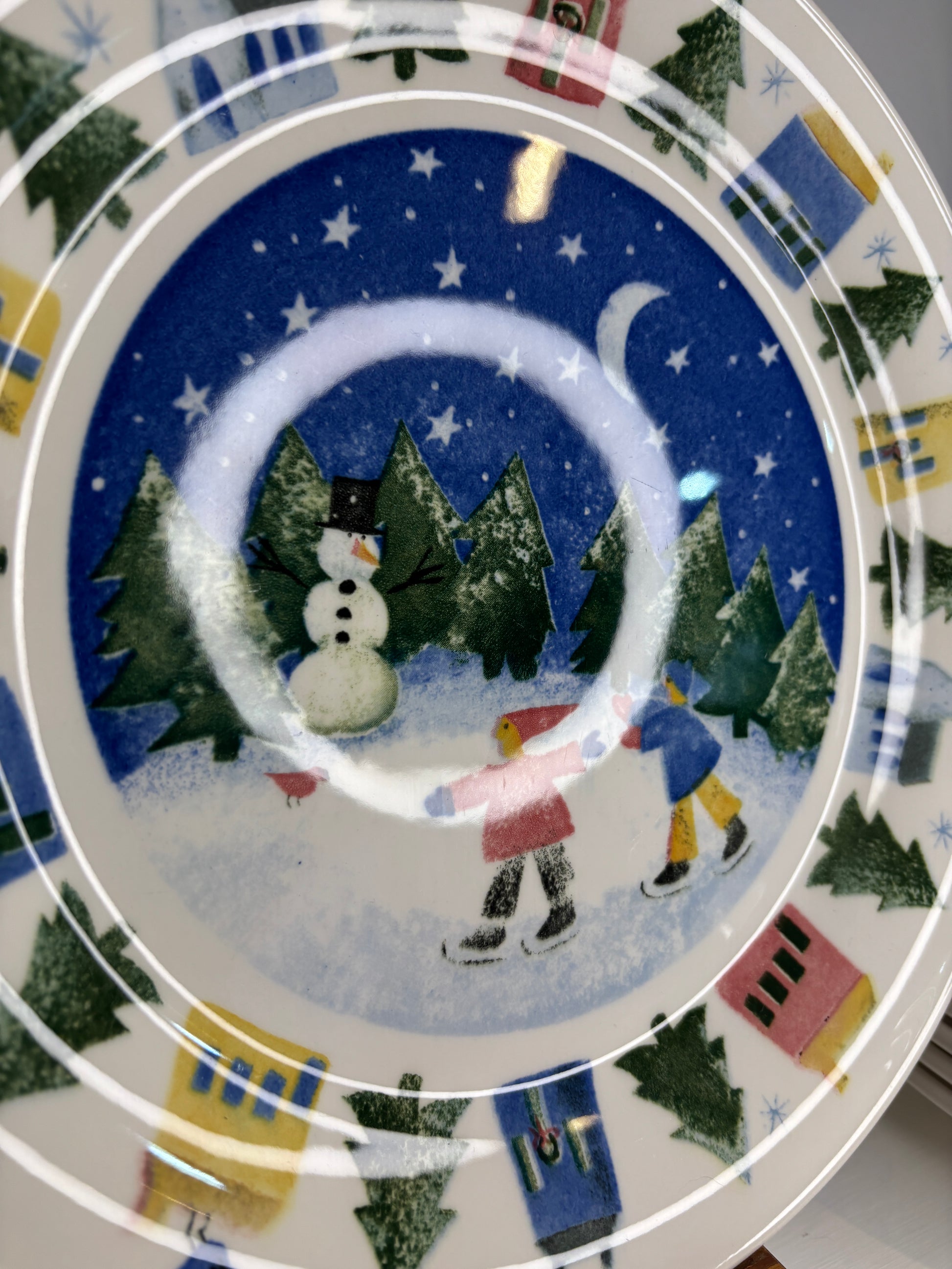 Decorative plate with Christmas-themed design featuring trees, snowmen, and houses.