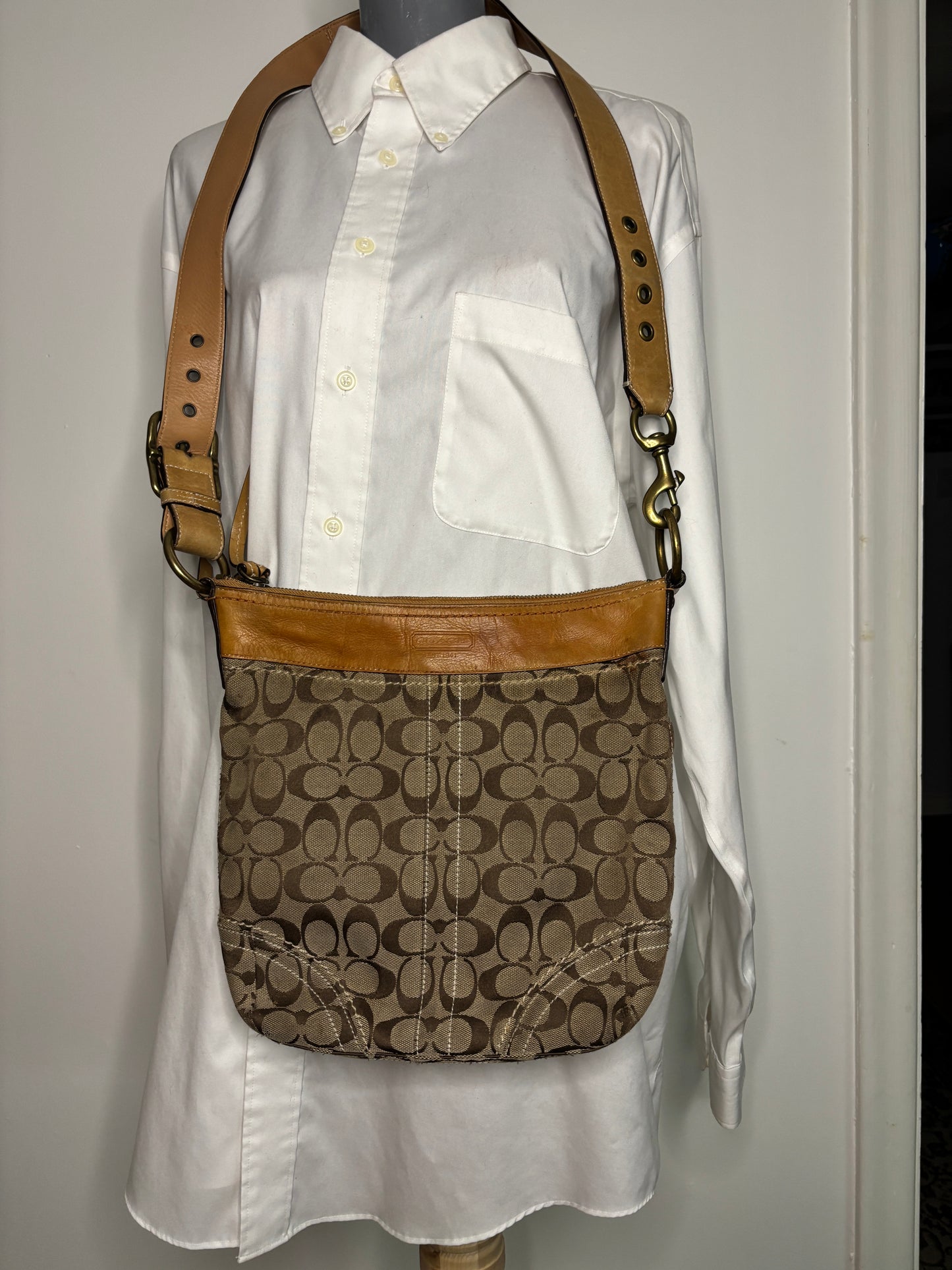 Coach handbag with brown leather strap on a white surface