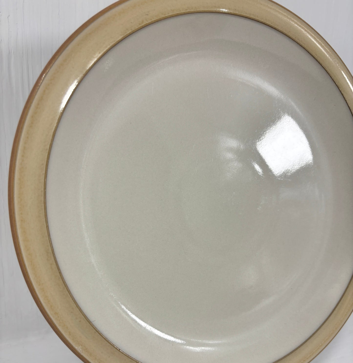White ceramic plate with brown rim on a white surface