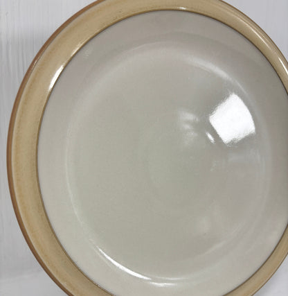 White ceramic plate with brown rim on a white surface