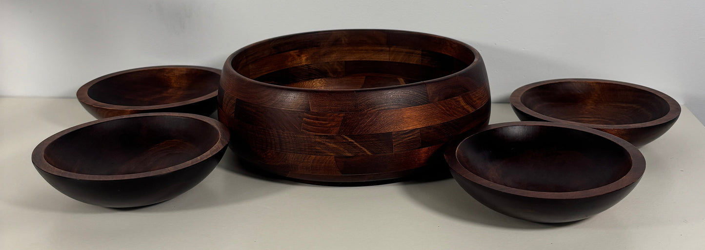 Set of wooden bowls stacked against a white wall