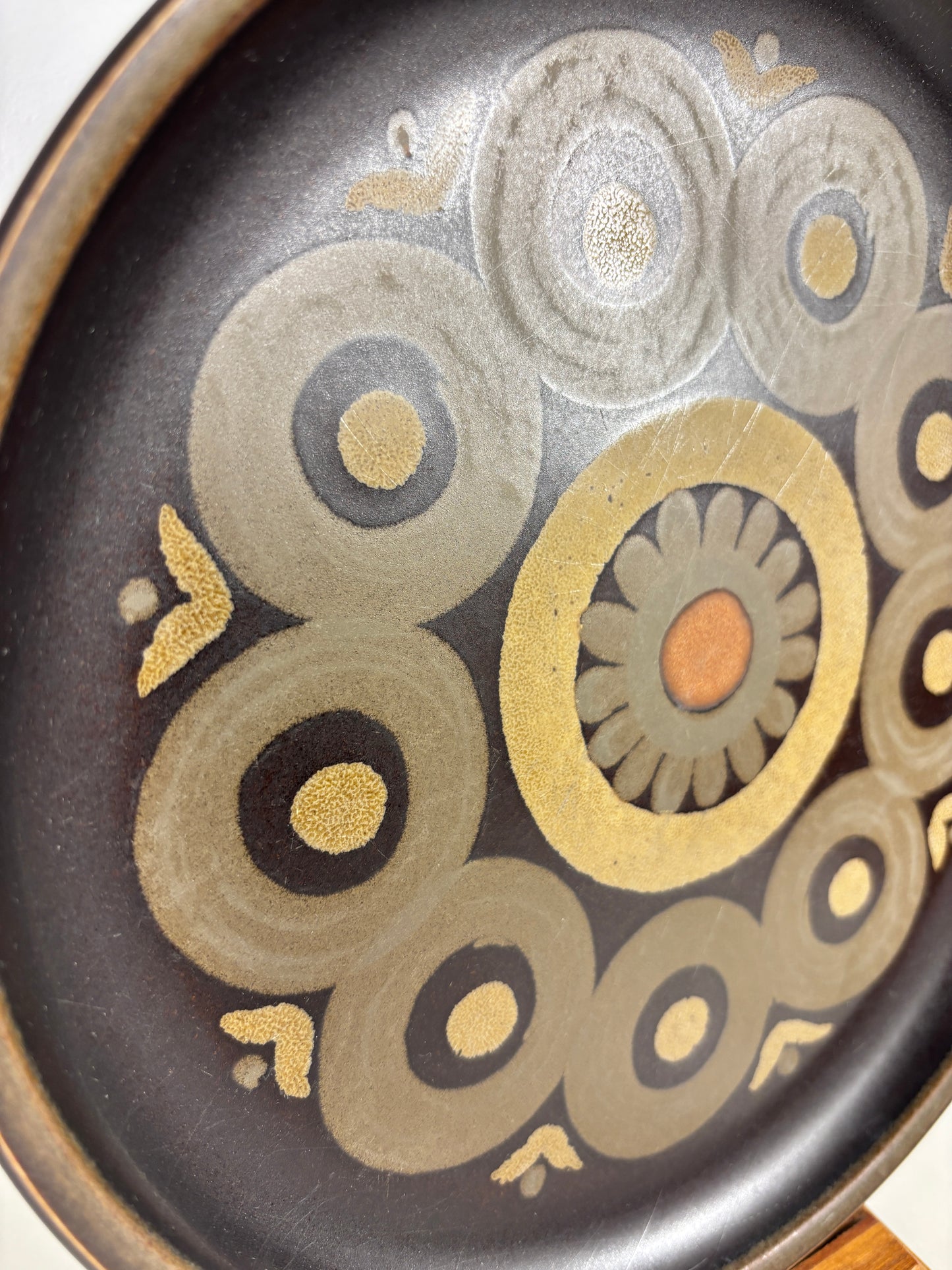 Decorative plate with circular patterns in gold, silver, and bronze on a black background