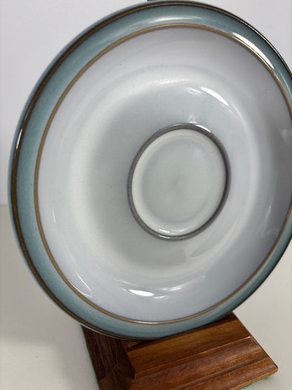 Ceramic saucer with a wooden coaster on a white surface