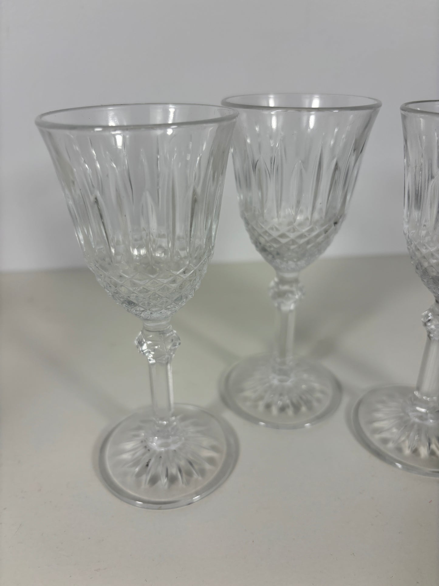 Three clear glass goblets with intricate designs on a white surface.