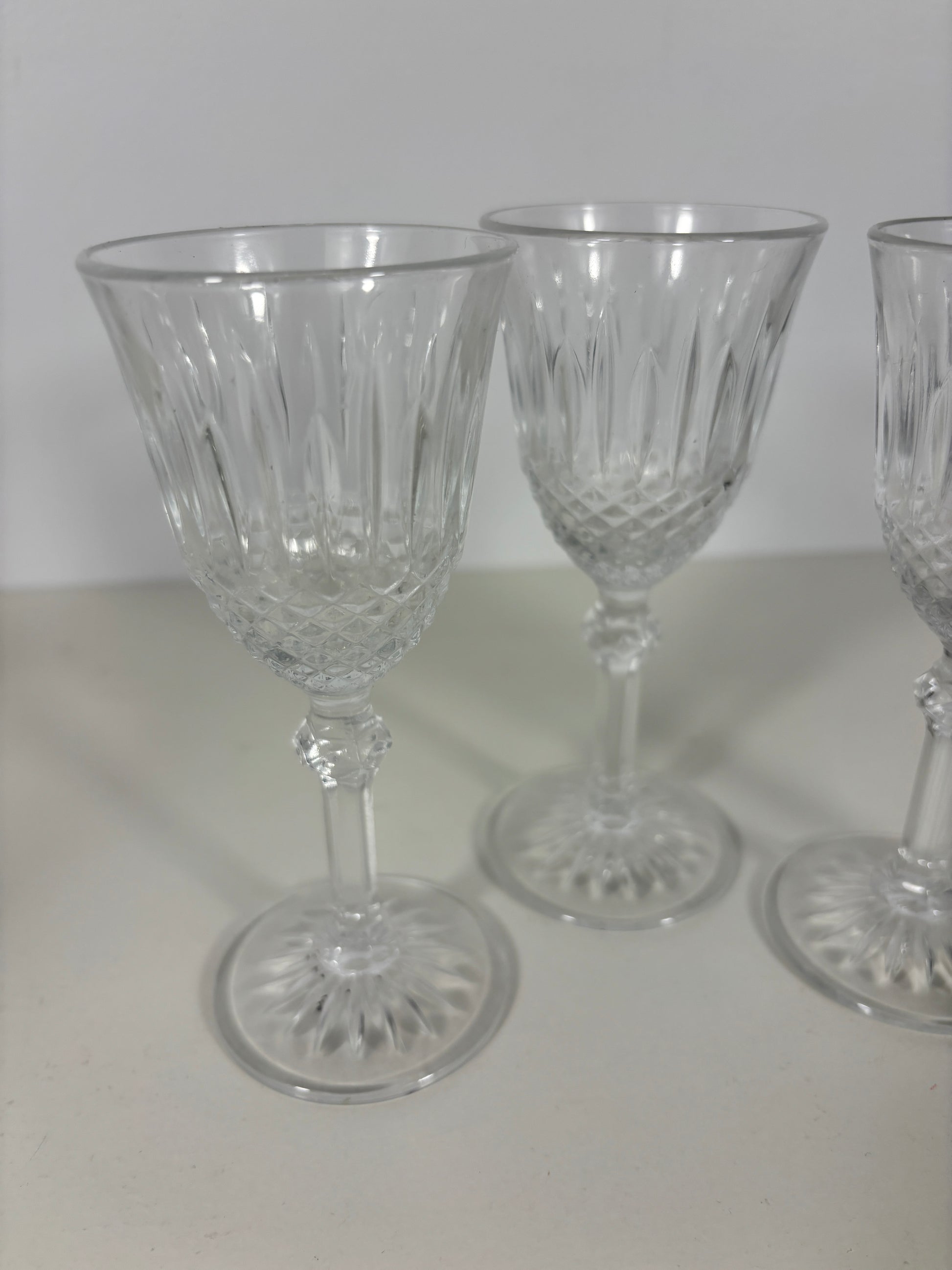 Three clear glass goblets with intricate designs on a white surface.