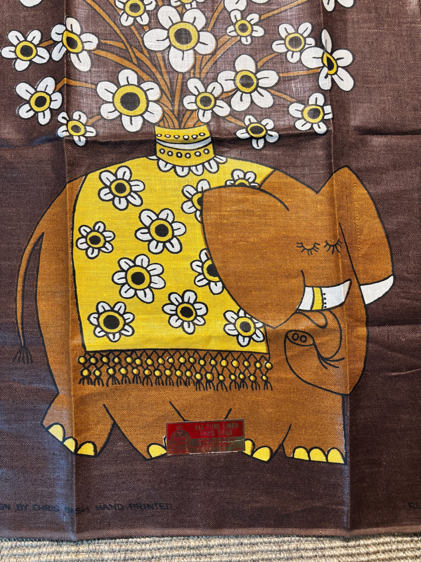 Decorative fabric with an elephant and floral design on a brown background