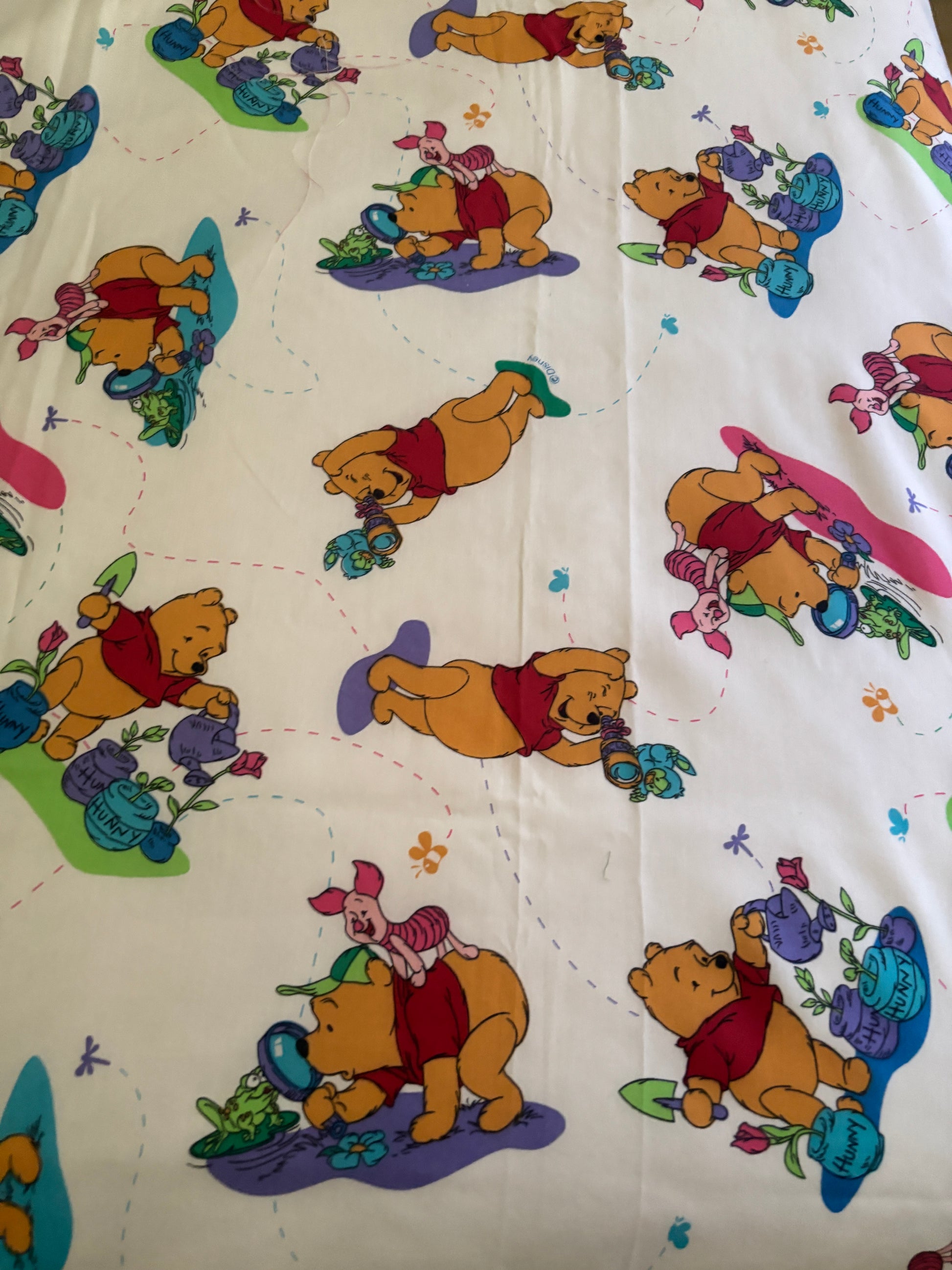 Fabric with colorful cartoon characters including a bear and piglet on a white background