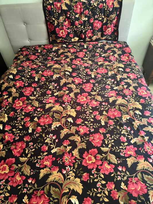 Floral patterned bedspread on a bed with a tufted headboard.
