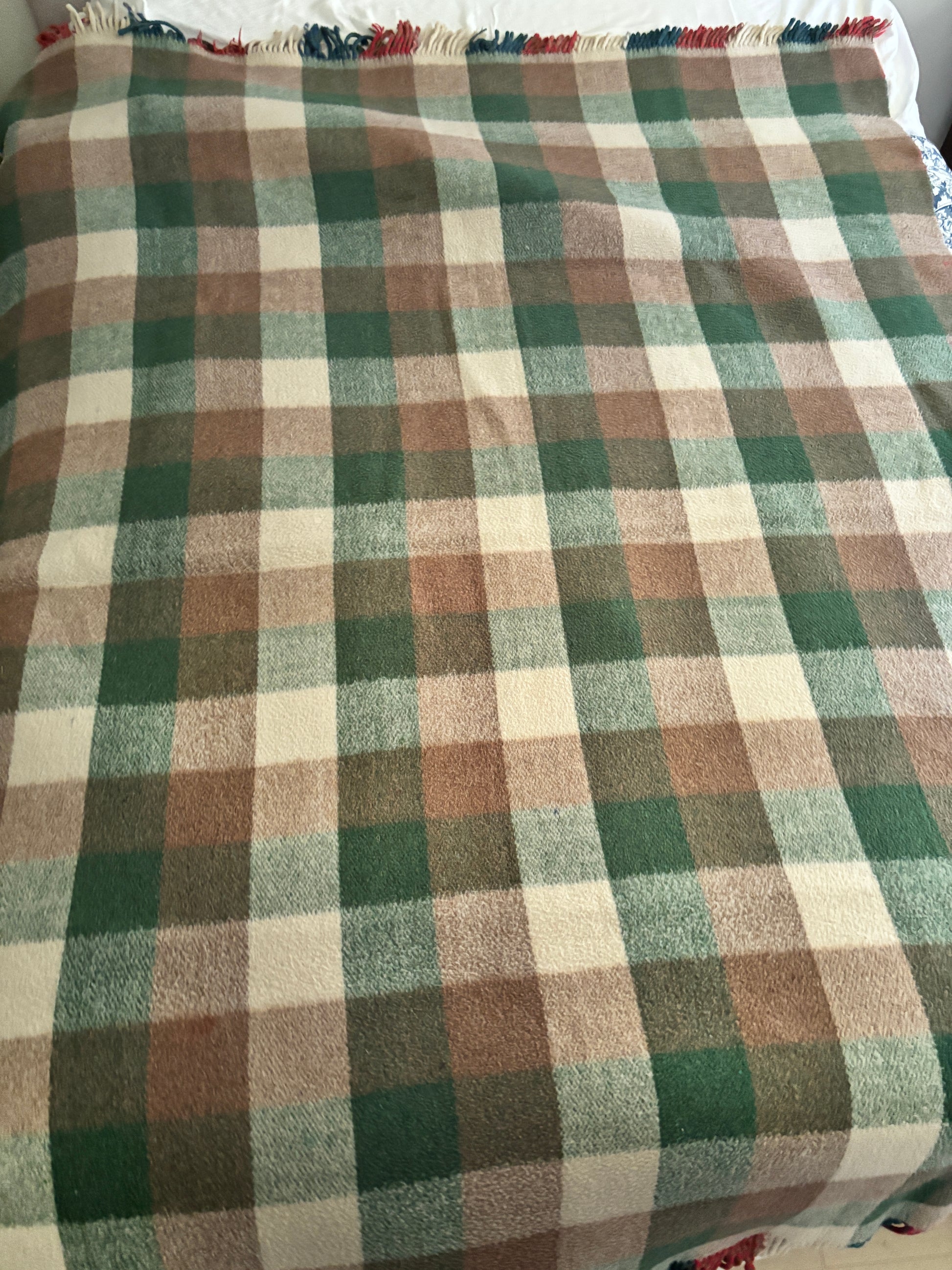 Plaid blanket with green, brown, and beige colors on a white background