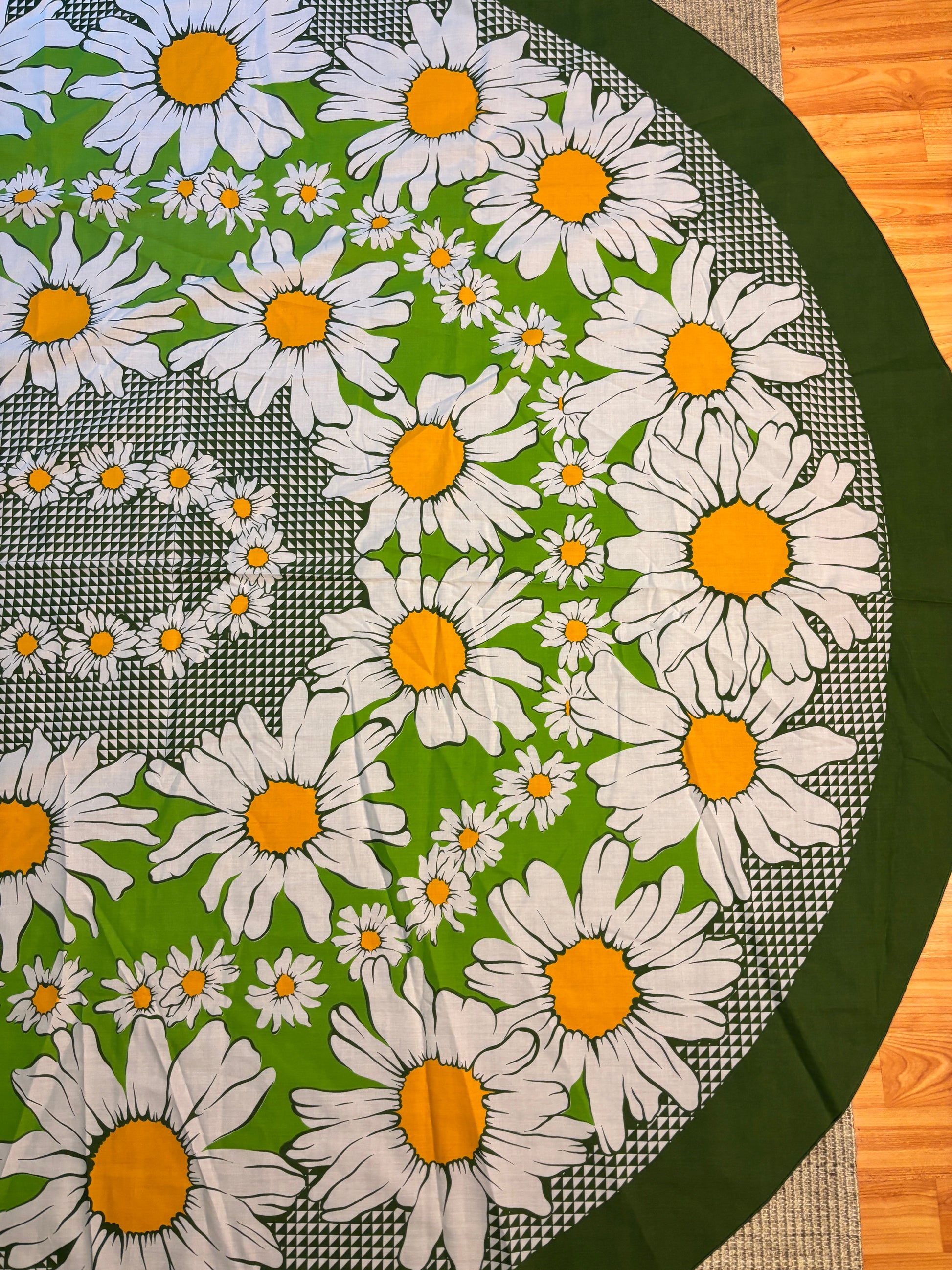Round tablecloth with white daisy pattern on a green background