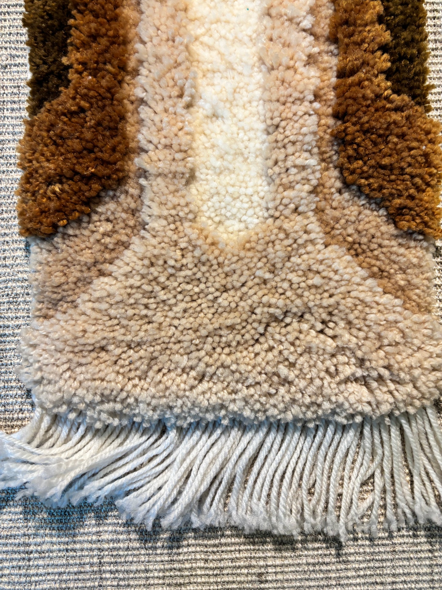 Close-up of a textured rug with brown, beige colors.