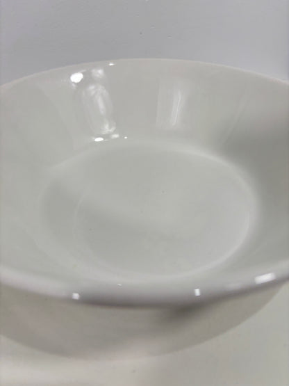 A close-up of a glossy white ceramic bowl or plate against a light gray background.