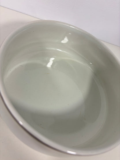 A white ceramic oval bowl with a glossy finish, photographed from a top-down angle on a white surface.