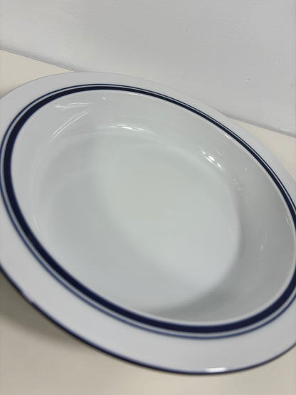 A white ceramic bowl with a double dark blue rim, shown from an overhead angle on a light-colored surface.
