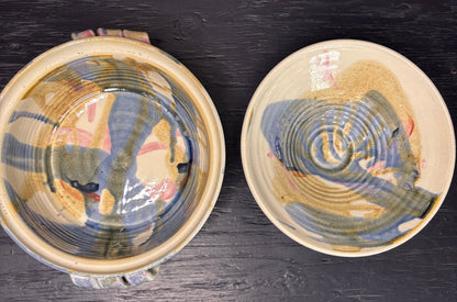 Two ceramic bowls with textured surfaces on a dark surface