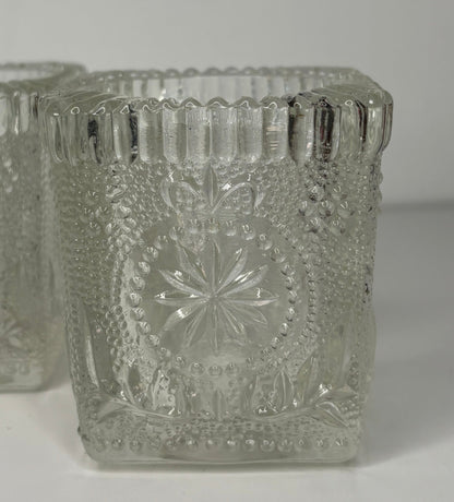 Decorative glass candle holders with intricate patterns on a white background
