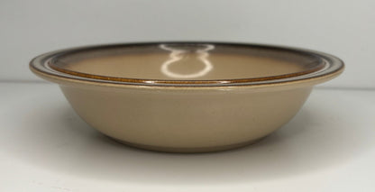 Beige ceramic bowl with brown rim on a white background