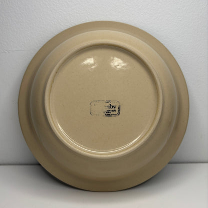 Beige ceramic plate with a visible brand logo on a white background