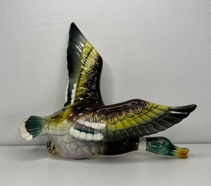 Decorative bird figurine with open wings on a white surface and light gray background