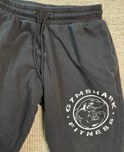 Black sweatpants with Gymshark Fitness logo on a textured surface