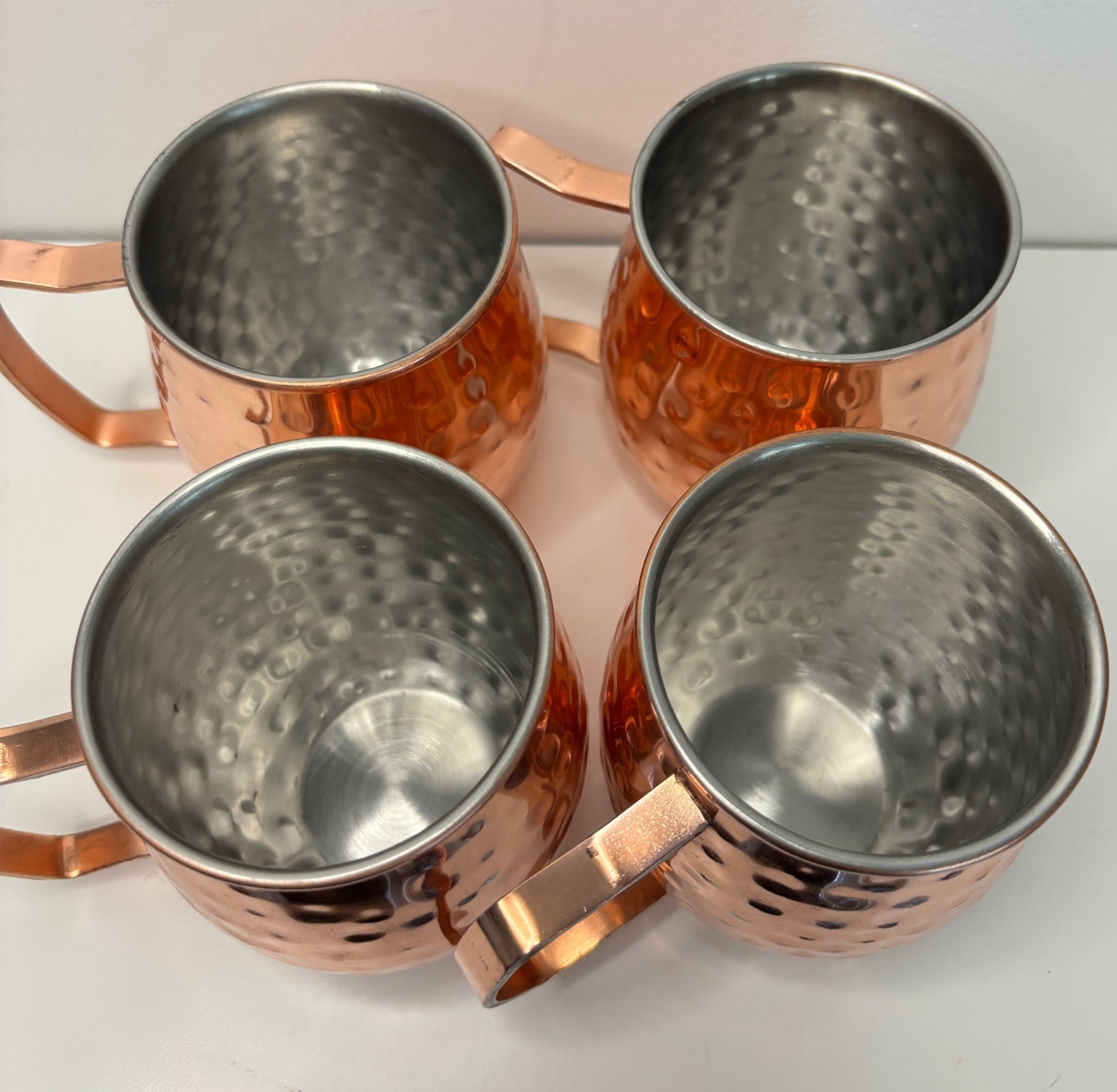 Four copper mugs with a hammered texture on a white background