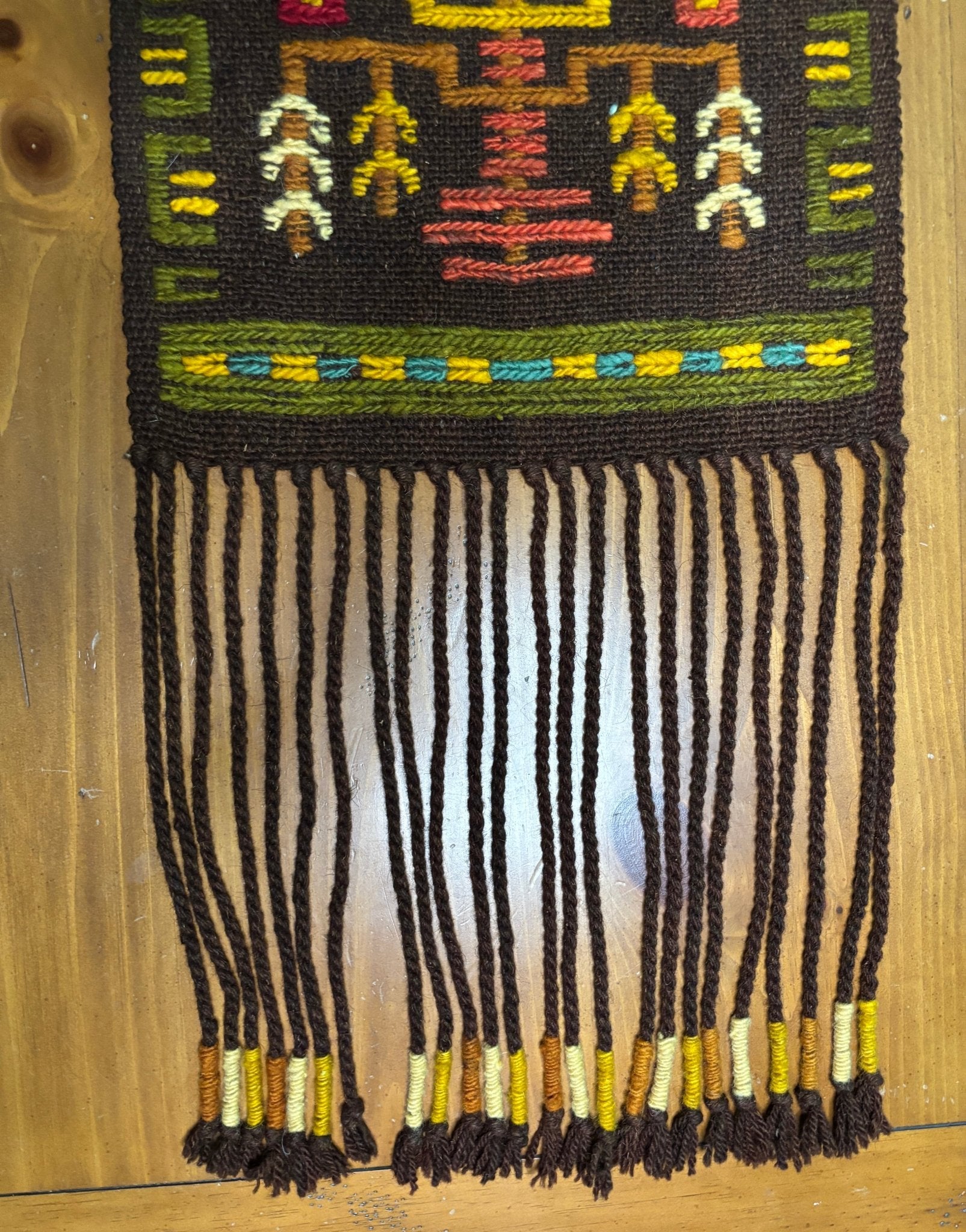 Textile with intricate patterns and fringes on a wooden surface