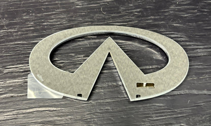 Metallic Infiniti logo on a wooden surface