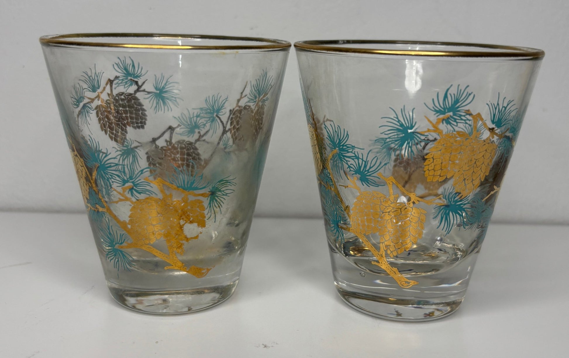 Two glass tumblers with deer and pine cone design on a white background