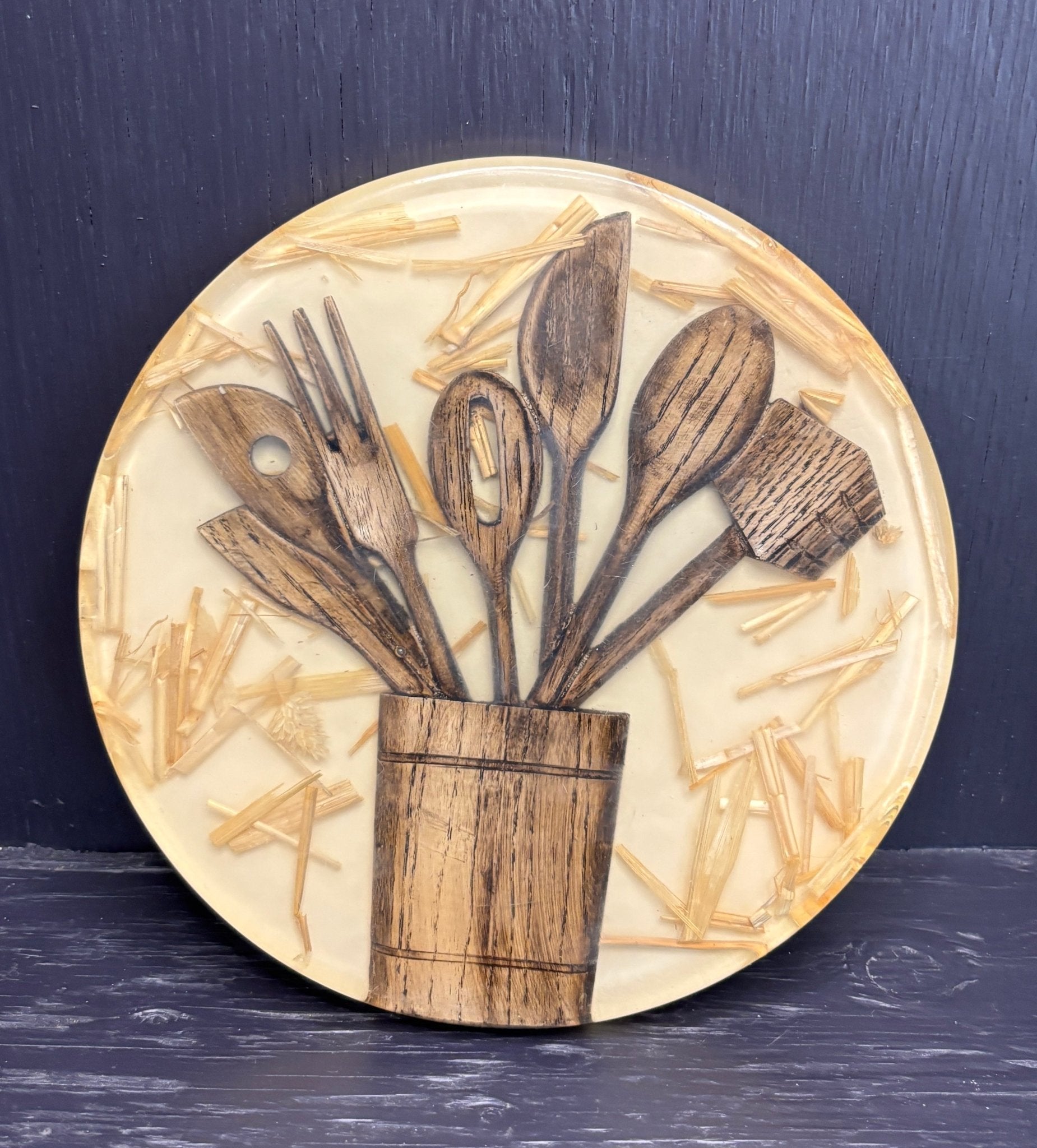 Round decorative pot stand with wooden cutlery design on a dark background