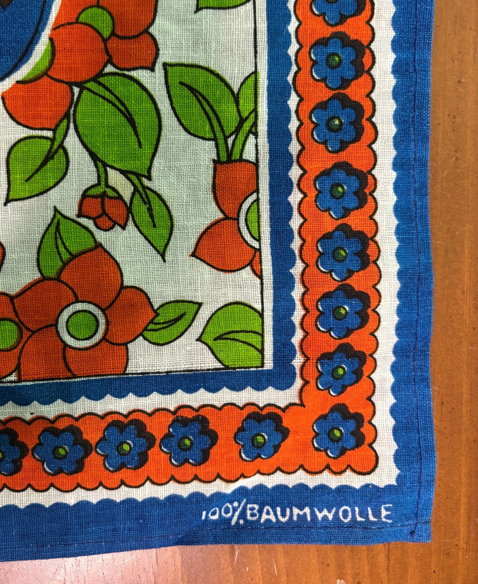 Fabric with floral pattern and blue border on a wooden surface