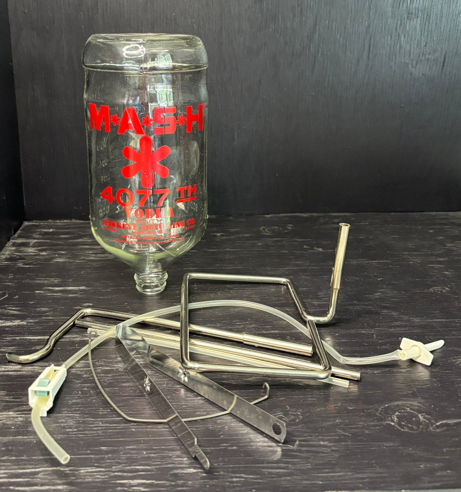 M*A*S*H 4077th medical bottle with IV stands on a dark surface