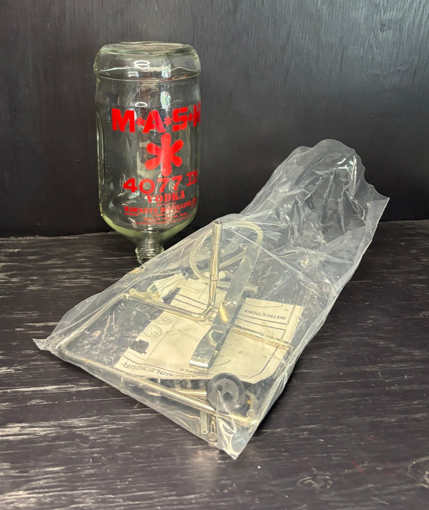 Clear plastic bag with vintage truck design on a dark surface, next to a glass bottle with 'Mack' branding.